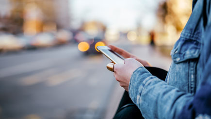 Person holding phone while waiting for car