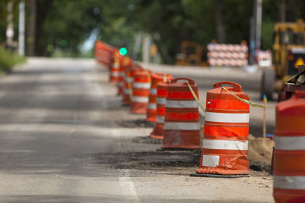 Orange and white work zone barrels lining the center of a road