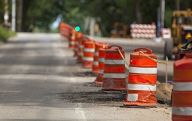 Orange and white work zone barrels lining the center of a road