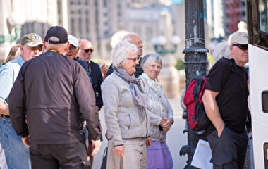 A group of older adults waiting to board a bus