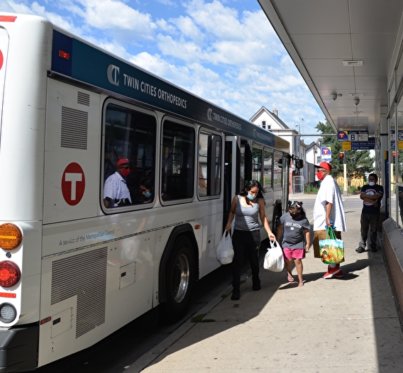 Passengers disembarking from a bus with shopping bags