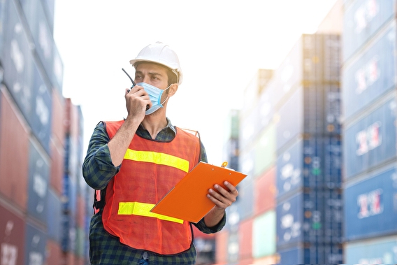 Man in a shipyard speaking into a radio