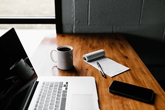 Laptop, smartphone, and cup of coffee sitting on a table in a home office