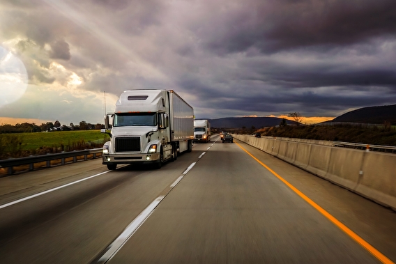 Two semi trucks driving on a divided highway