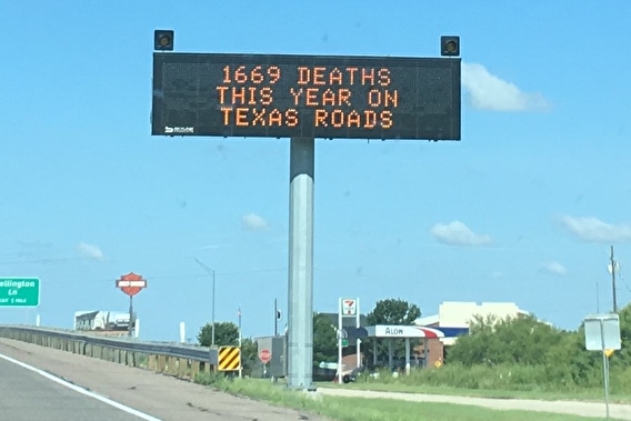 A roadside electronic messaging sign reading "1669 deaths this year on Texas roads"