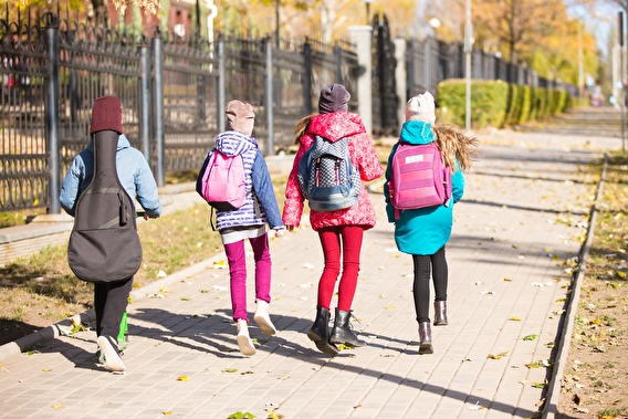 A group of children walking to school on a sidewalk