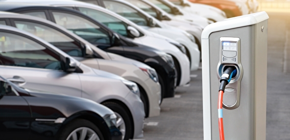 A row of cars parked by an electric vehicle charging station