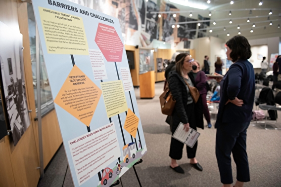 Attendees talking next to a poster at the Our Transportation, Our Lives event